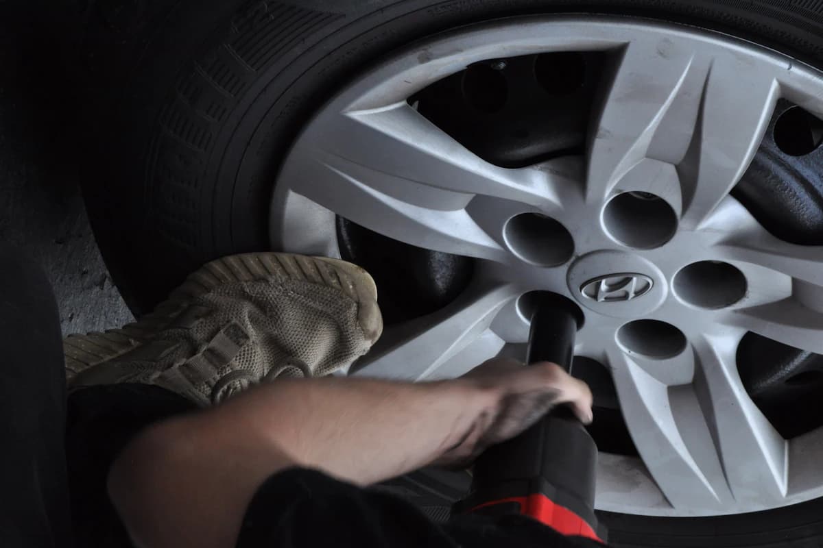 Mobile tyre fitter replacing a car tyre at the customer's location